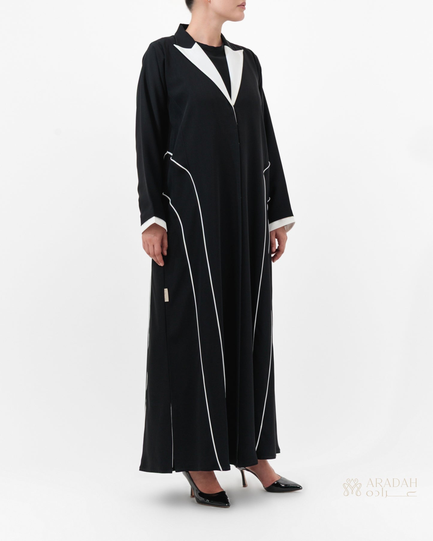 Black abaya with white accents worn by a model on a white background