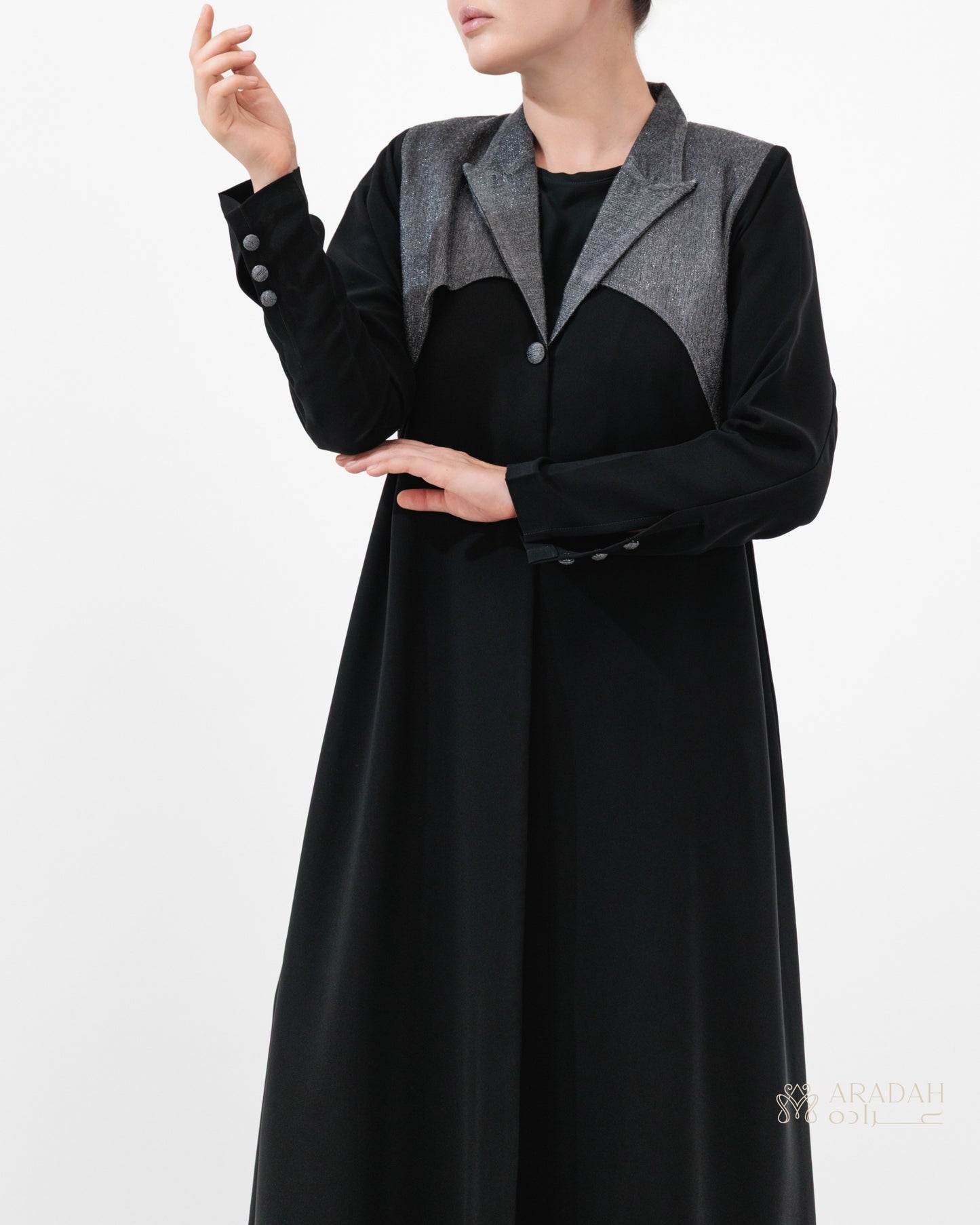 Black coat with gray lapels worn by a person on a white background
