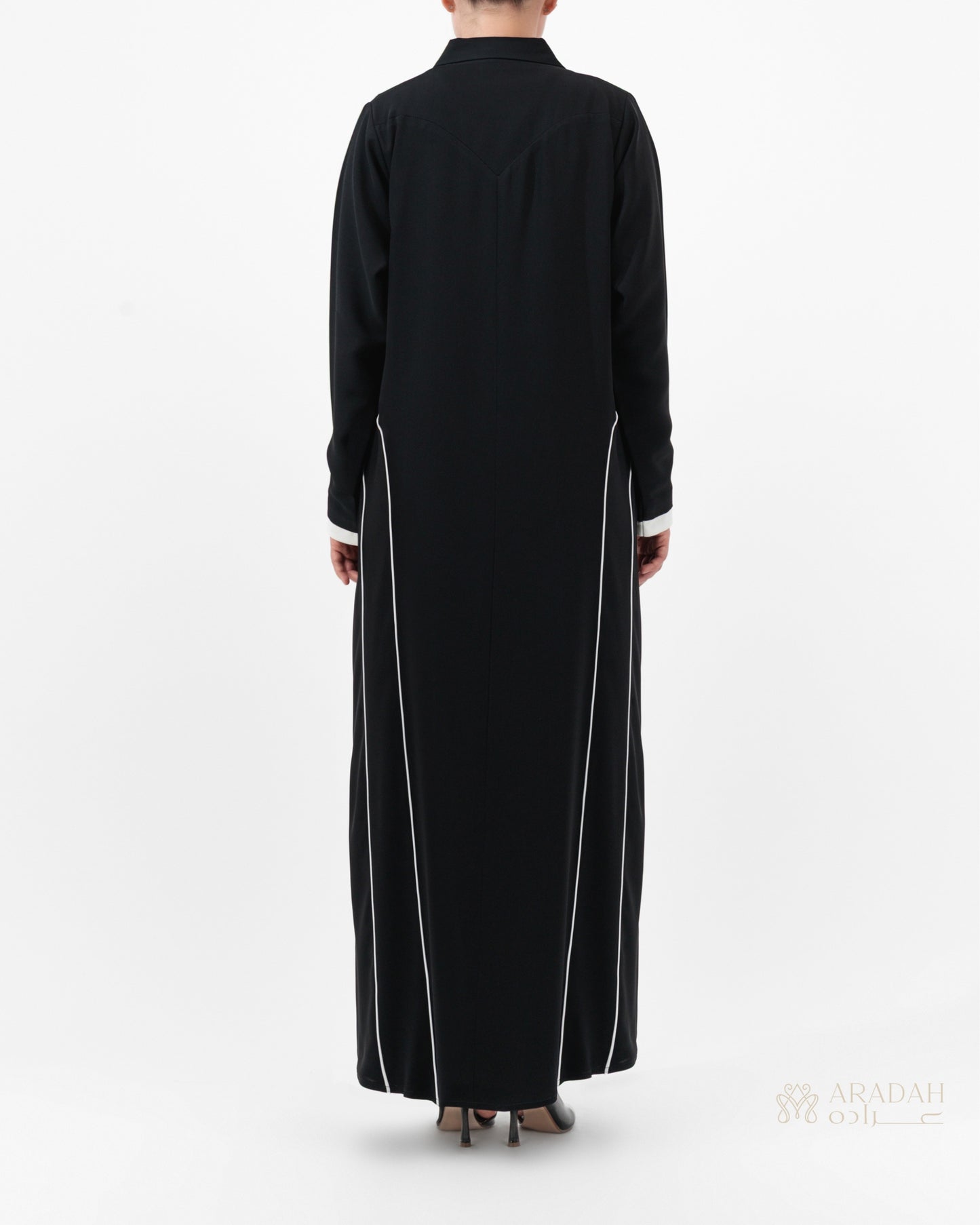 Black long-sleeve dress with white trim on a white background